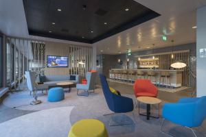 eine Lobby mit Stühlen, Tischen und einer Bar in der Unterkunft Holiday Inn Express - Luzern - Kriens, an IHG Hotel in Luzern