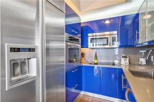 a kitchen with blue cabinets and a stainless steel refrigerator at 1201 W Residences in Fort Lauderdale