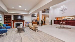 a living room with a fireplace and blue furniture at Best Western Plus Villa Del Lago Inn in Patterson