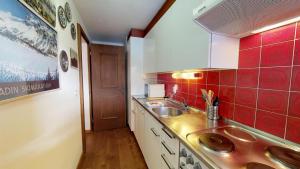 eine kleine Küche mit einer Spüle und roten Fliesen in der Unterkunft Quadratscha - Samedan in Samedan
