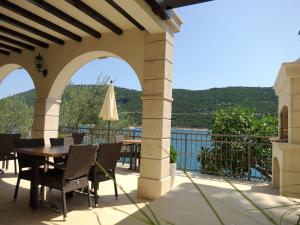 a patio with a table and chairs and a view of the water at Guest House Villa Maslina Neum in Neum