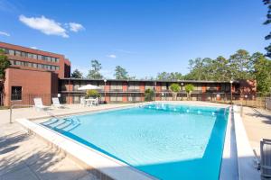 a large swimming pool in front of a building at Days Inn & Suites by Wyndham Tallahassee Conf Center I-10 in Tallahassee