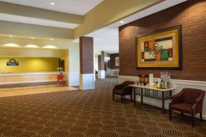 a lobby with a waiting room with chairs and a table at Days Inn & Suites by Wyndham Tallahassee Conf Center I-10 in Tallahassee