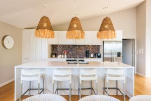 a kitchen with a large white island with bar stools at Luxury at Palm Beach - You've Got It Maid in Palm Beach