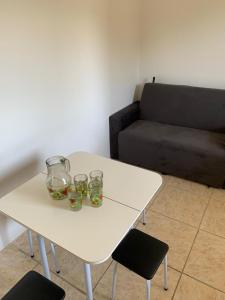 uma mesa branca com dois copos e um sofá em Ap beira da Praia das Ondinas em São Lourenço do Sul