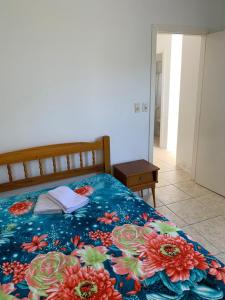 a bedroom with a bed with a floral blanket at Apartamento beira da Praia das Ondinas in São Lourenço do Sul