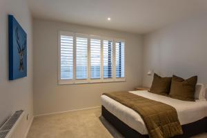 a bedroom with a bed and a window at Waipatiki by Sotheby's Luxury Rental Homes in Queenstown