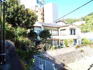 uma casa com uma cerca em frente a um edifício em Guesthouse Nishihara em Atami