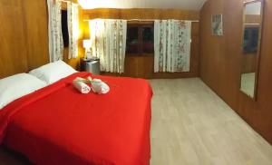 a bedroom with a red bed with two stuffed animals on it at Matira house in Bora Bora