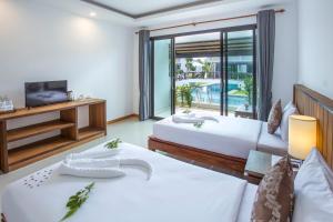 a hotel room with two beds and a tv at The La Valle'e Resort in Khao Lak