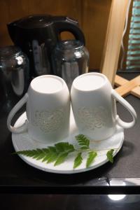 two white mugs sitting on a plate on a table at Matira house in Bora Bora