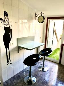 een kamer met twee krukken en een tafel met een vrouw aan de muur bij Alójate en Vigo! Piso moderno y funcional in Vigo