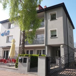 a white building with a tree in front of it at Willa Nest in Unieście