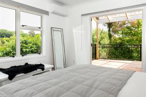 a white bedroom with a bed and a balcony at The House at No 1 in Havelock North