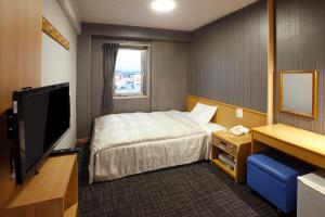 a hotel room with a bed and a television at Sakudaira Plaza 21 in Saku