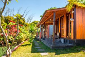 a small wooden house with a porch in a garden at Black Lava Hostel and Lodge in Kintamani