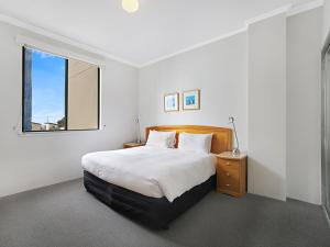 a white bedroom with a bed and a window at AeA The Coogee View in Sydney