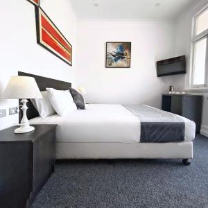 sypialnia z dużym białym łóżkiem i lampką w obiekcie Commercial Motel w mieście Hay