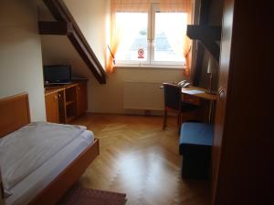 a bedroom with a bed and a desk and a window at Gästehaus Einzinger in Krems an der Donau