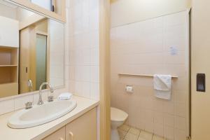 a bathroom with a sink, toilet and mirror at Carrum Downs Motel in Carrum Downs