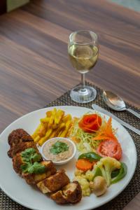 a white plate of food with a glass of wine at Hotel Snow Peak in Pokhara