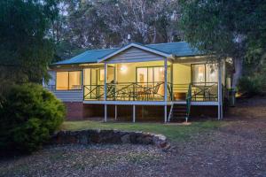 una pequeña casa amarilla con porche y escalera en Bushy Lake Chalets, en Margaret River Town