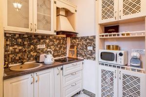 ブカレストにあるPrivate Museum Apartment with Antique Decorの白いキャビネットとシンクと電子レンジを備えたキッチン
