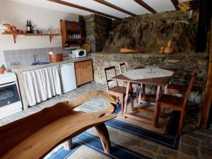 uma cozinha com uma mesa e cadeiras e uma parede de pedra em Bairro do Casal - Turismo d'Aldeia em Vila Nova de Foz Côa