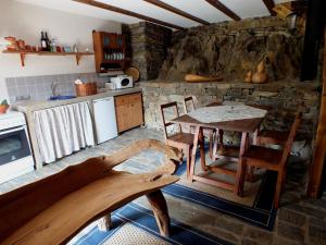 a kitchen with a table and chairs and a stone wall at Bairro do Casal - Turismo d'Aldeia in Vila Nova de Foz Coa