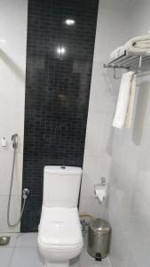a bathroom with a toilet and a black tiled wall at Rouba Residency Hotel in Ponnāni
