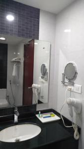 een badkamer met een wastafel en een spiegel bij Rouba Residency Hotel in Ponnāni