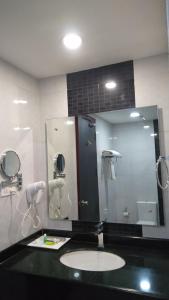 a bathroom with a sink and a large mirror at Rouba Residency Hotel in Ponnāni