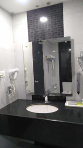 a bathroom with a sink and a mirror at Rouba Residency Hotel in Ponnāni