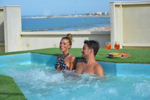 a man and a woman sitting in a swimming pool at AmbientHotels Panoramic in Rimini