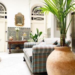 ein Wohnzimmer mit einem Sofa und einer Topfpflanze in der Unterkunft Hotel Boutique Casa de Colón in Sevilla