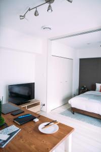 Un dormitorio con una cama y un escritorio con televisión. en Dash Living Nihonbashi, en Tokio
