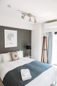 Un dormitorio con una gran cama blanca con una manta azul. en Dash Living Nihonbashi, en Tokio