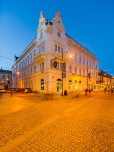 ein großes weißes Gebäude in einer Kopfsteinpflasterstraße in der Unterkunft Hotel Imparatul Romanilor in Sibiu