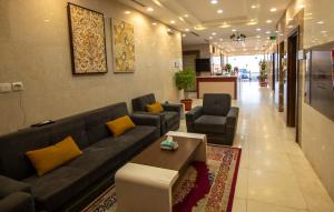 Waha AL Mudaif Serviced Apartments في تبوك: غرفة معيشة مع أريكة وكرسيين