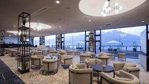 un ristorante con sedie, tavoli e finestre di Aki Grand Hotel & Spa a Miyajima