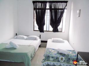 two beds in a room with a window at Hotel El Descanso in San José