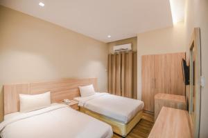 a hotel room with two beds and a tv at Grand Flora Salalah in Salalah