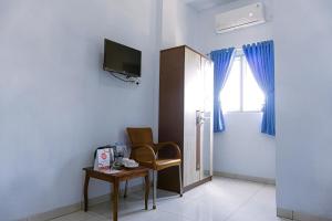 a room with a chair and a table and a television at SUPER OYO 1565 Hotel Homiko in Pacitan