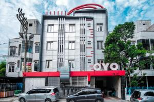 a building with cars parked in front of it at OYO 279 Deli Homestay in Medan