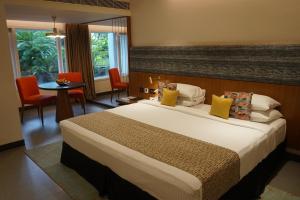 a hotel room with a bed and a table and chairs at Casino Hotel - CGH Earth, Cochin in Cochin