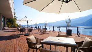a patio with tables and chairs and a view of the water at Aki Grand Hotel & Spa in Miyajima