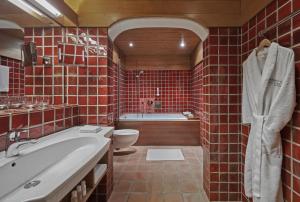 W wyłożonej czerwonymi kafelkami łazience znajduje się wanna i toaleta. w obiekcie Hotel Goldener Greif w mieście Kitzbühel