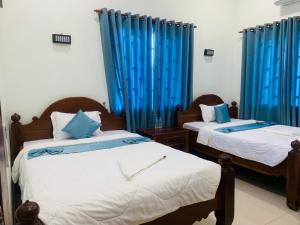 two beds in a room with blue curtains at Mama's Family Guesthouse in Kampot