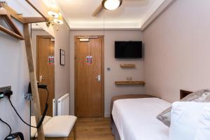 - une chambre avec un lit et une télévision murale dans l'établissement Arosfa Hotel London by Compass Hospitality, à Londres