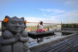 a woman sitting on a table next to a statue at Purana Suite Ubud in Ubud